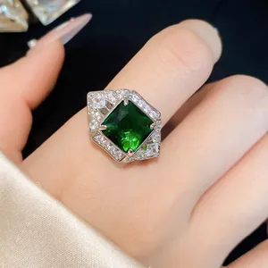 Close-up of a square green zircon ring with micro-paved small stones on a finger