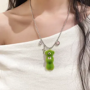 Close-up detail of cute green plush bear necklace with zircon heart and star charms