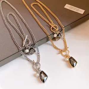 Detail view of gold and silver chain necklaces with irregular crystal pendants and pearls.