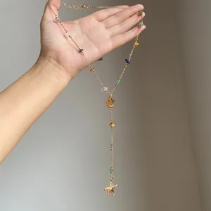 Dettaglio di una collana dorata con perle di pietra colorate, conchiglia e stella