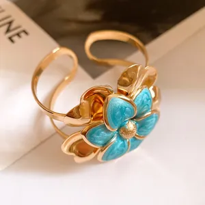 Macro detail showing the blue enamel double-layer flower on vintage gold open bangle.
