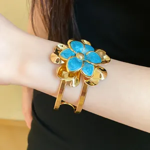 Close-up of vintage gold cuff bracelet with blue and gold double-layer flower design