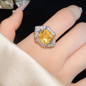 Close-up view of a luxury square yellow zircon ring with halo crystals on a finger
