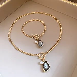 Detail view of vintage gold curb chain necklace and bracelet set with pearl and grey stone.
