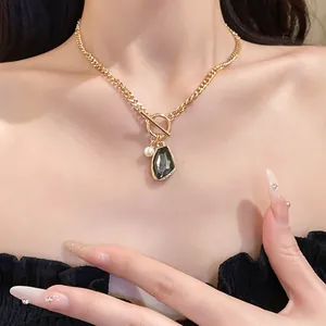 Elegant gold chain necklace with irregular dark stone and pearl pendant on model