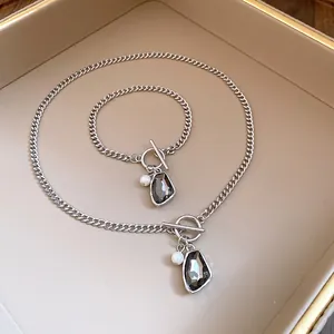 Detailed view of vintage silver chain jewelry set with grey crystal and pearl pendants.