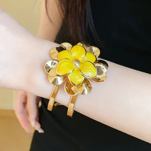 Close-up of vintage golden cuff bracelet with double-layer yellow enamel flower