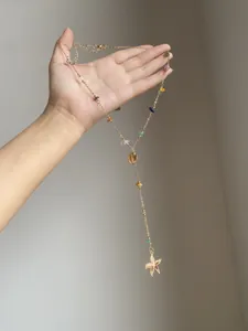 Dettaglio di una collana di perline dorate con ciondoli a conchiglia e stella marina.