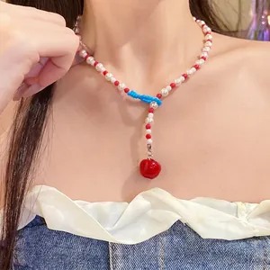 Collana di perle con ciondolo a mela rossa e perline blu indossata da modella