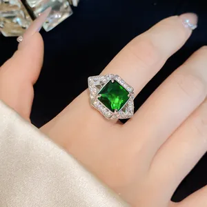 Detailed view of an emerald green square zircon ring worn on a hand with satin background.