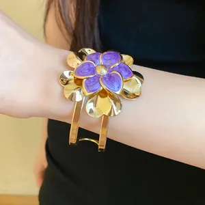 Close-up of vintage gold flower cuff bracelet with purple enamel petals on wrist