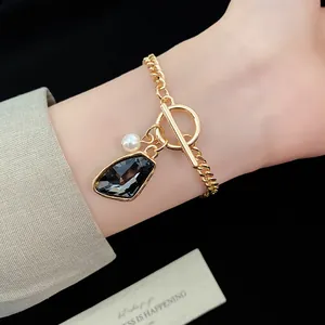 Detailed view of vintage gold chain bracelet with pearl and grey gemstone pendant charms