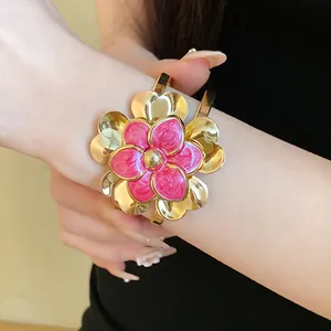 Detail view of a vintage gold bangle featuring a pink enamel double-layer flower.