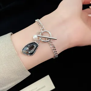 Detailed shot of a silver chain bracelet with irregular dark crystal and pearl charm