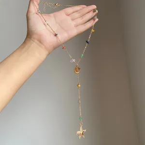 Dettaglio della collana dorata con perle colorate, pendenti a conchiglia e stella