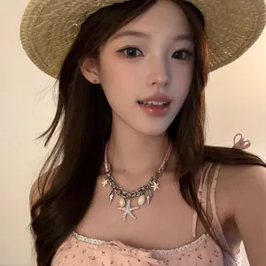 Détail d'un collier en cuir rose avec étoile de mer et coquillages sur un modèle
