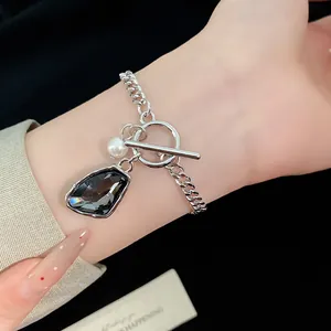 Close-up of silver chain bracelet with irregular grey gemstone and pearl pendant.