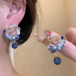 Detailed close-up of vintage resin rose earrings with pearl and blue bead accents