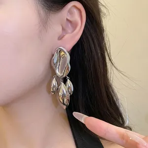 Modern irregular geometric shiny silver twisted drop earrings worn by a female model