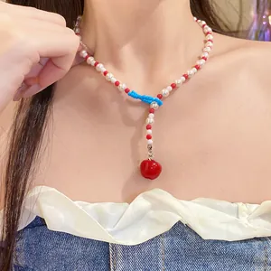 Primo piano di una dolce collana di perle a forma di mela rossa indossata da una modella