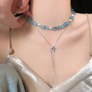 Dettaglio ravvicinato di una collana a due strati con pietre blu e ciondolo a stella marina lucente.