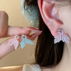 Close-up shot of colorful handmade seed bead fishtail stud earrings worn on an ear