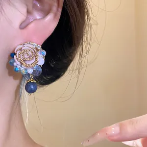 Detail shot of elegant French vintage rose earrings with blue beads and resin pearls.