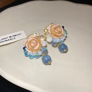 Close-up detail of French vintage resin rose stud earrings with iridescent crystals and pearls
