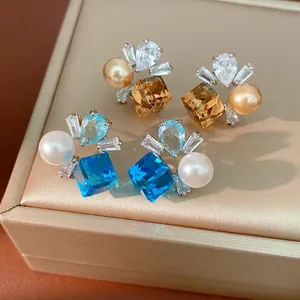 Nahaufnahme von eleganten Ohrsteckern mit blauen und champagnerfarbenen Zirkonia und Perlen