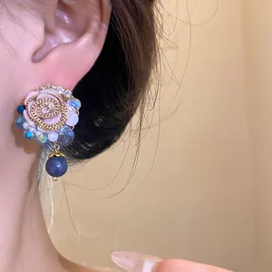 Close-up detail of retro floral resin earrings with blue crystal accents and dangling bead