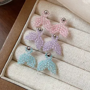 Macro view of handmade seed bead fishtail stud earrings in three soft pastel colors