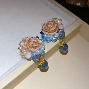 Detailed macro view of vintage resin rose stud earrings with elegant blue beads and pearls