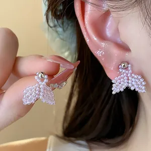 Close-up detail of handmade pink rice bead fishtail stud earrings on ear.