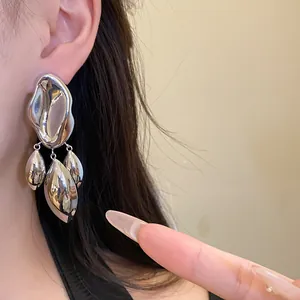 Close-up view of shiny silver irregular geometric pendant earrings worn by a model