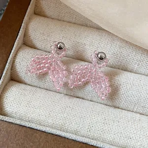 Close-up detail of handmade pink beaded fish tail stud earrings inside a jewelry box