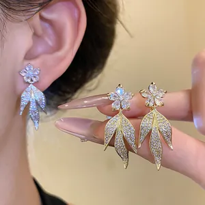 Detail view of elegant 14k gold plated zircon flower and leaf earrings on model