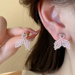 Close-up detail of delicate pink seed bead fishtail earrings with silver needles on ear.