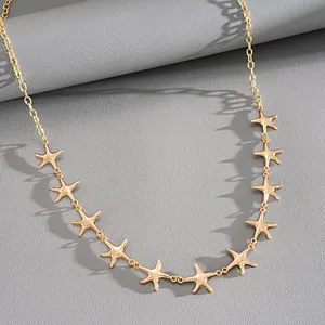 Detail shot of a gold-finish starfish charm necklace on a textured grey background