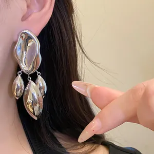 Close-up view of elegant irregular liquid metal silver drop earrings shown worn on an ear