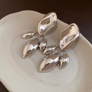 Close-up of irregular geometric silver earrings with a polished molten metal texture