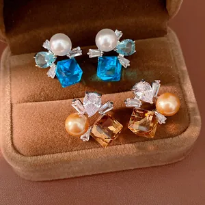 Nahaufnahme eleganter Perlenohrringe mit blauen und champagnerfarbenen Zirkoniasteinen