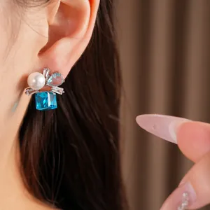 Detailansicht eines eleganten Silberohrrings mit blauem Edelstein und weißer Perle