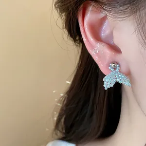 Exquisite close-up of light blue beaded fishtail stud earrings with silver needles.