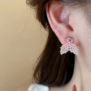 Macro detail view of a pink hand-beaded fishtail stud earring on a model's ear
