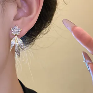 Close-up of elegant 14k gold-plated zircon flower tassel earrings on ear with crystal leaves