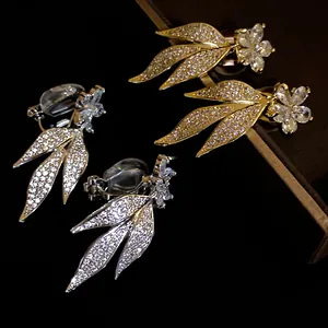 Close-up of 14k gold plated cubic zirconia floral leaf clip-on earrings in gold and silver