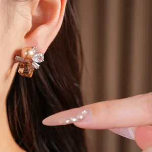 Nahaufnahme eleganter Ohrstecker mit Perle, Zirkonia und bernsteinfarbenem Stein