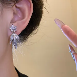 Close-up of elegant flower and leaf tassel earrings with sparkling zirconia stones.