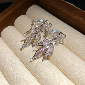 Macro shot of silver-plated clip-on earrings featuring sparkly zircon flower and leaf motifs
