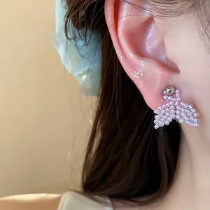Detailed close-up of handmade purple seed bead fishtail stud earrings on ear